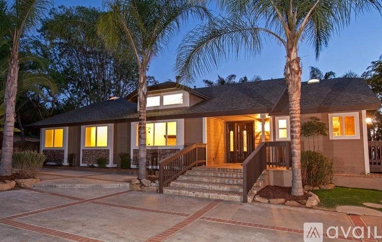 A house with a driveway and palm trees in front.