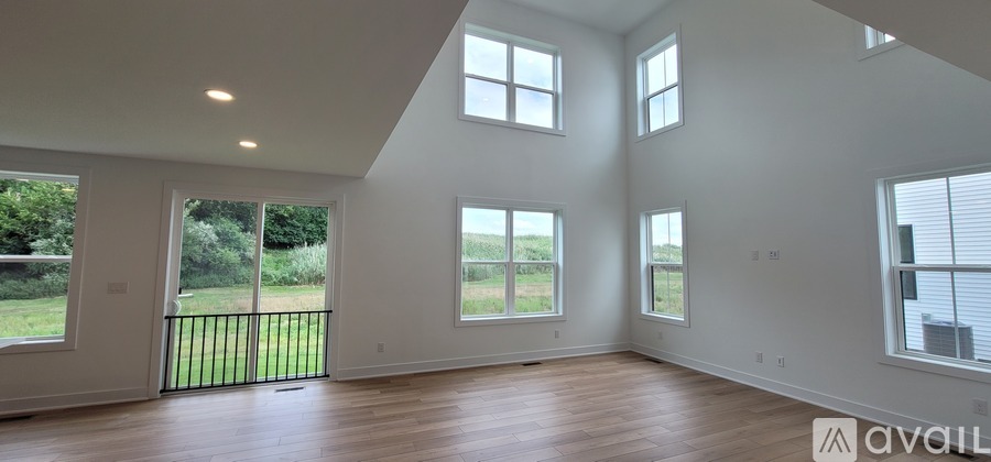 A spacious room with wooden floors and large windows.