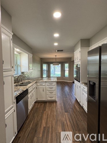 A modern kitchen with white cabinets and a wooden floor.