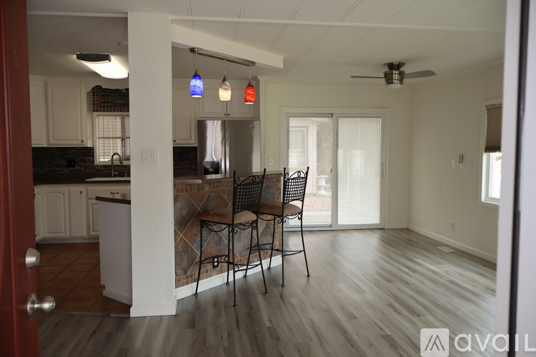 A kitchen with a dining table and chairs is visible through a doorway.