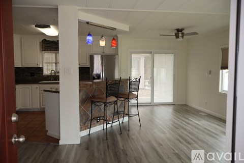 A kitchen with a dining table and chairs is visible through a doorway.