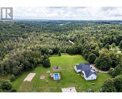 An aerial view of a property with a swimming pool and a house surrounded by trees.