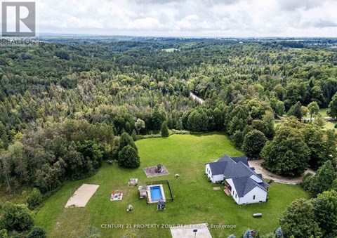 An aerial view of a property with a swimming pool and a house surrounded by trees.