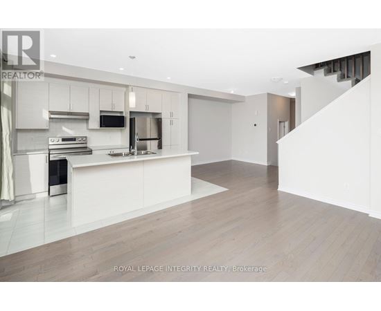 A modern kitchen with white cabinets and a wooden floor.