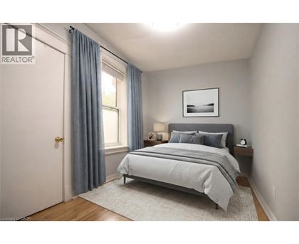 A bedroom with a bed, nightstand, and window.