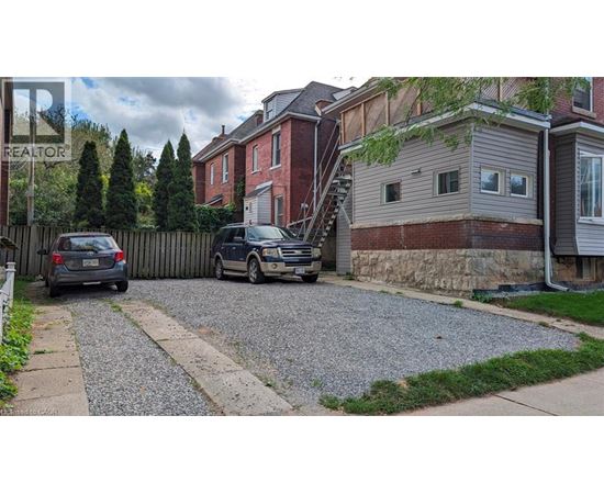 A gravel driveway leads to a house with a car parked on the side.