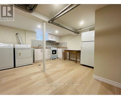 A kitchen area with white appliances and wooden flooring.