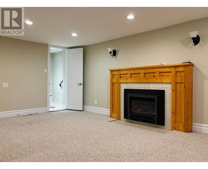 A room with a fireplace and a doorway leading to another room.