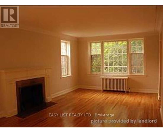 A room with a fireplace and a window with a view of trees.