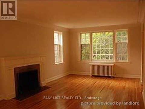 A room with a fireplace and a window with a view of trees.