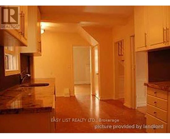 A real estate listing image of a kitchen with wooden cabinets and a marble countertop.