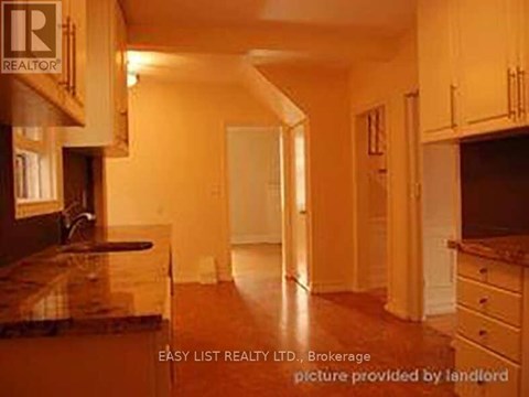 A real estate listing image of a kitchen with wooden cabinets and a marble countertop.