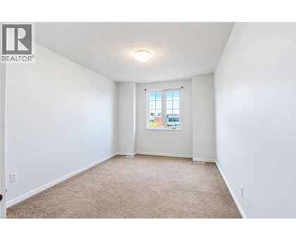 A white room with a carpeted floor and a window.