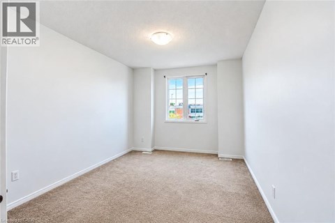 A white room with a carpeted floor and a window.