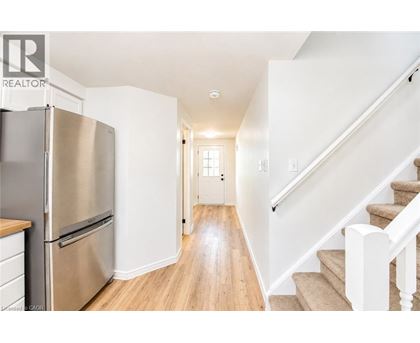 A stainless steel refrigerator sits in a kitchen with wooden floors and white walls.