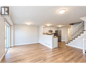 A spacious living room with hardwood floors and a staircase leading to the upper level.
