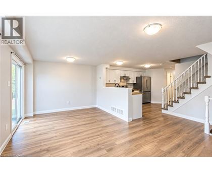 A spacious living room with hardwood floors and a staircase leading to the upper level.