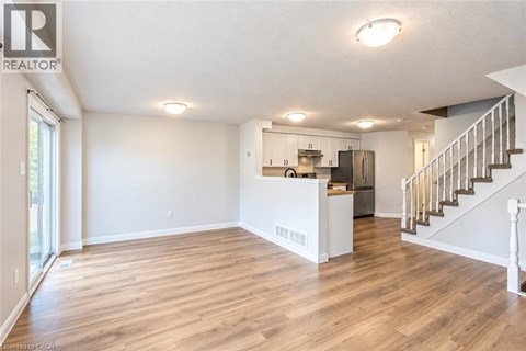 A spacious living room with hardwood floors and a staircase leading to the upper level.