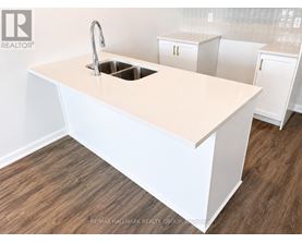 A white kitchen island with a sink and cabinets in the background.