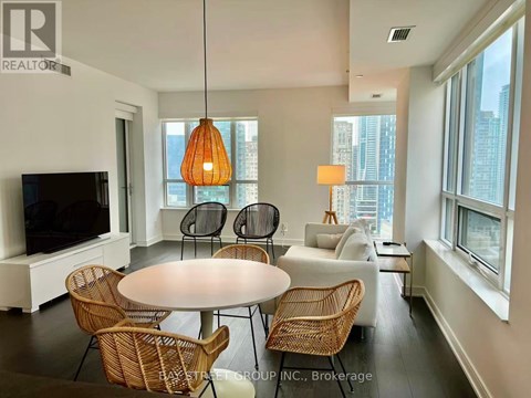 A living room with a white table and chairs, a television, and a large window.