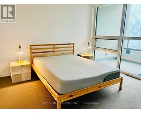 A bedroom with a bed, nightstand, and window.