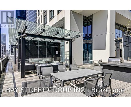 A modern outdoor dining area with a glass roof and a view of the city.
