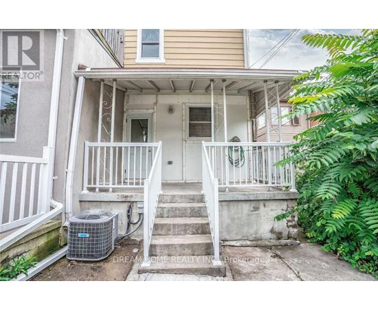 A front porch with a white railing and steps leading to a door.