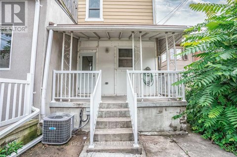 A front porch with a white railing and steps leading to a door.