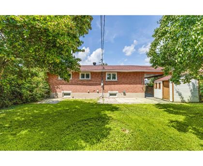 A house with a red brick exterior and a green lawn.