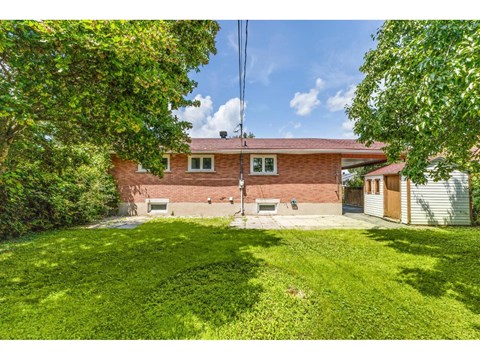 A house with a red brick exterior and a green lawn.