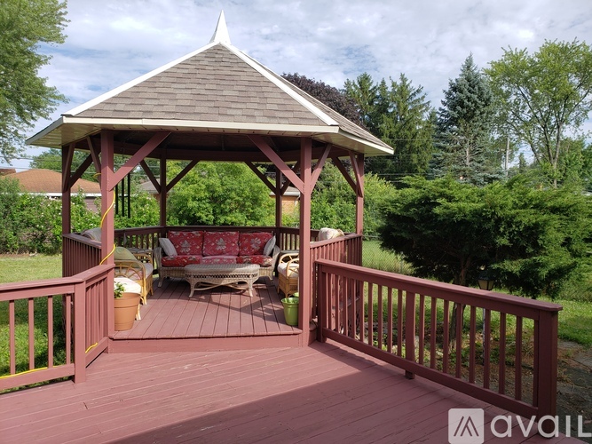 A gazebo with a red roof and wooden deck.