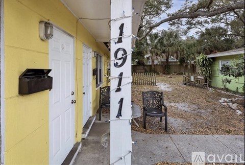 A yellow house with a white door and a black chair in front of it.