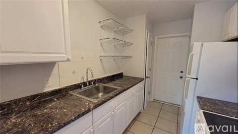 A kitchen with white cabinets and a black granite countertop.