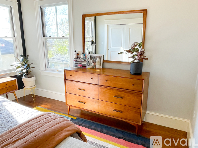 A bedroom with a wooden dresser and a mirror.