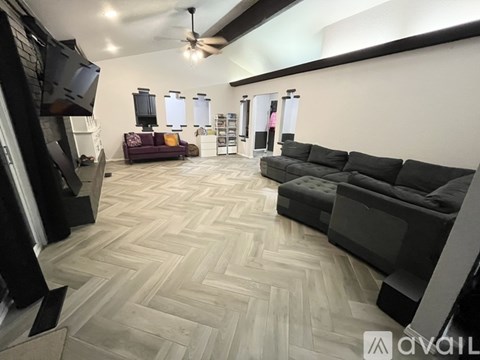 A living room with a black couch and a chevron patterned floor.