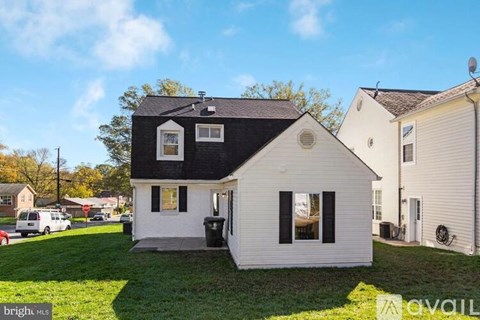 A house with a black roof and white walls is for sale.