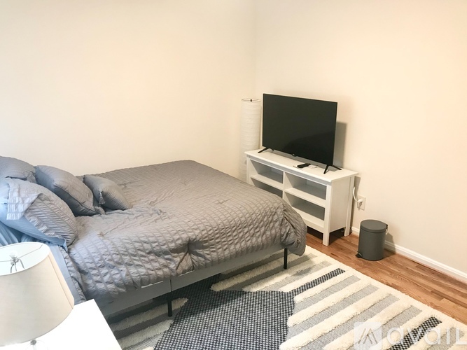 A bedroom with a bed, a television, and a trash can.