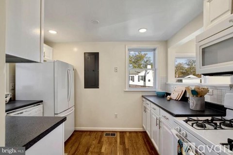 A kitchen with white cabinets and a black countertop.
