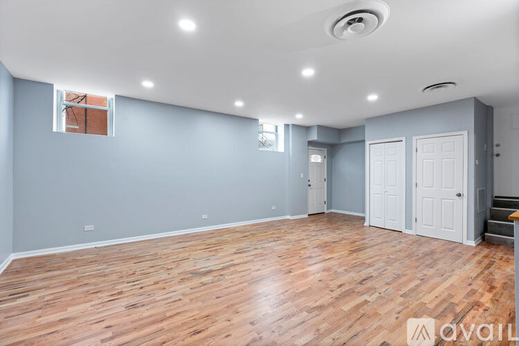 A spacious room with wooden flooring and white walls.