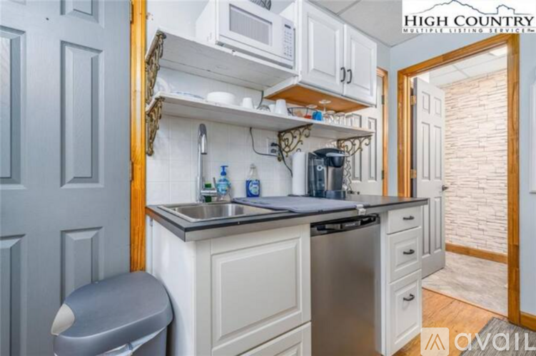 A kitchen with white cabinets and a wooden framed mirror above the sink.