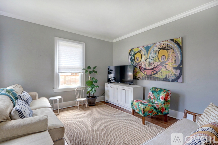 A living room with a couch, chair, and a painting on the wall.
