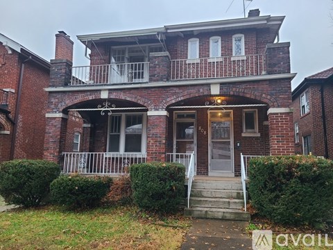 A red brick house with a balcony and a door.