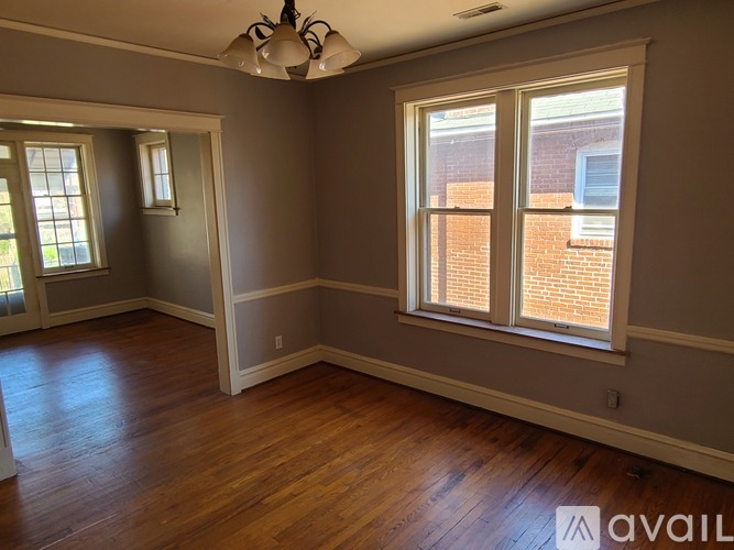 A room with wooden floors and a large window with a view of a brick building.