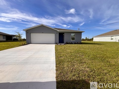 A house with a grey roof and a white garage door is surrounded by a grassy area.