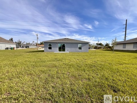 A small house with a grey roof is situated in a grassy field.