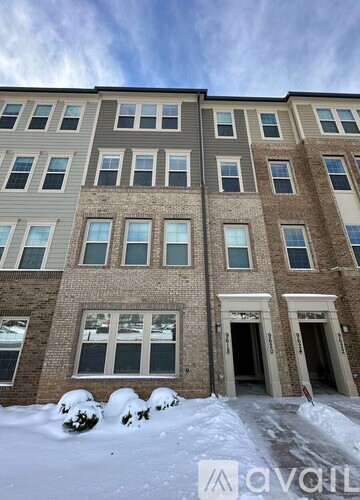 A large building with a row of windows and a snowy ground in front.
