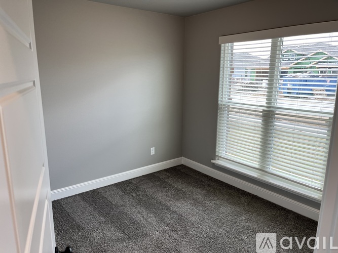 A room with a carpeted floor and a window with blinds.