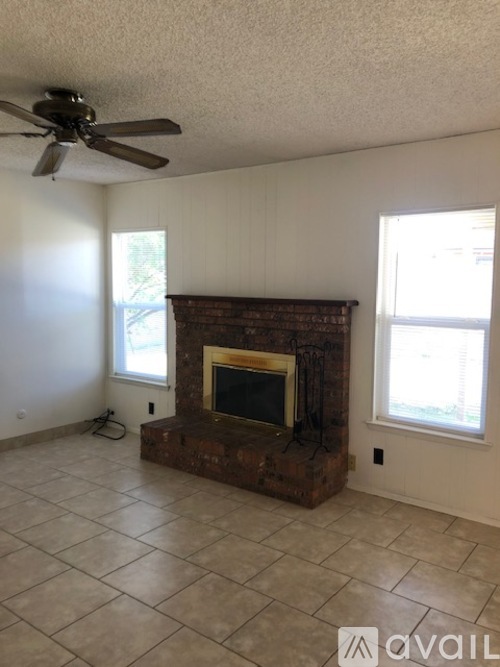 A living room with a fireplace and a ceiling fan.