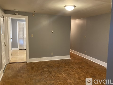A room with wooden flooring and a door leading to another room.