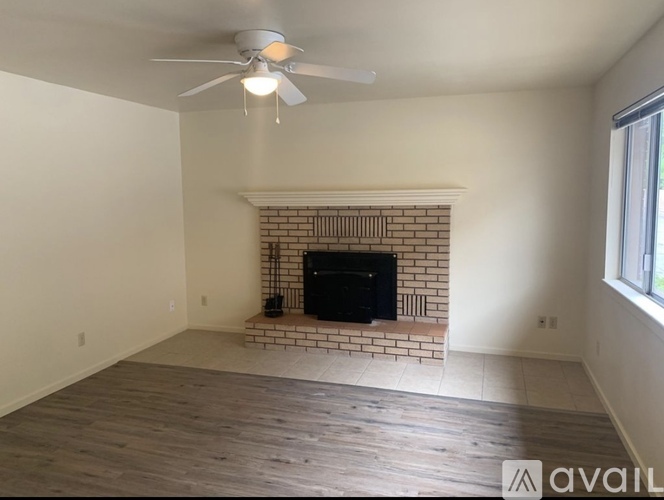 A living room with a fireplace and a ceiling fan.